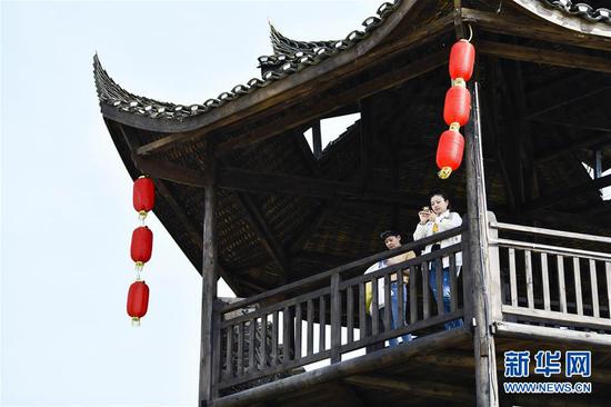  游客在重慶市武隆區(qū)黃鶯鄉(xiāng)復(fù)興村的觀景樓上欣賞田園景色（2019年3月28日攝）。 新華社記者 劉潺 攝
